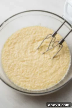 Creamed butter and sugar in a glass mixing bowl with an electric handheld mixer.