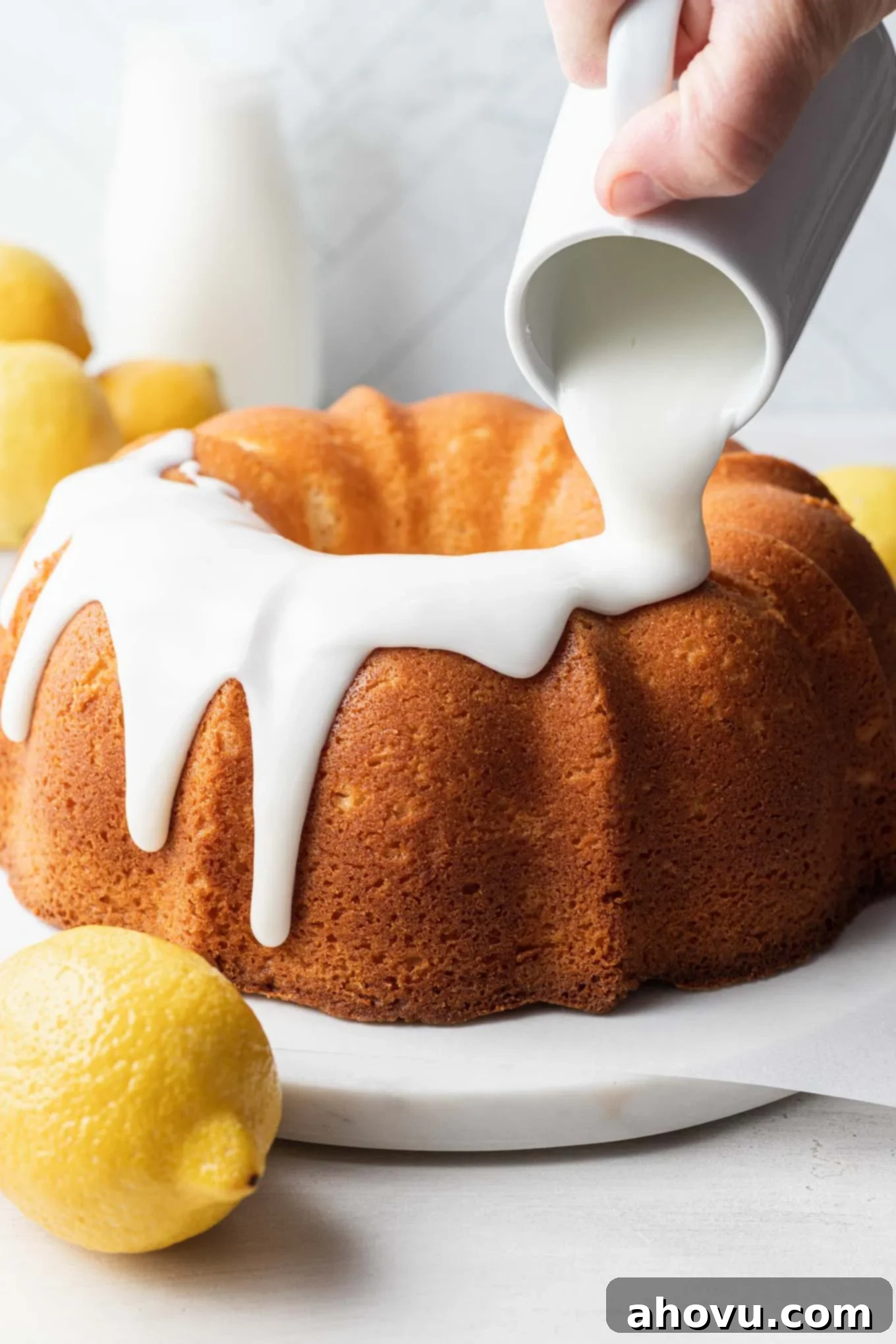 Lemon glaze being poured over a pound cake. 