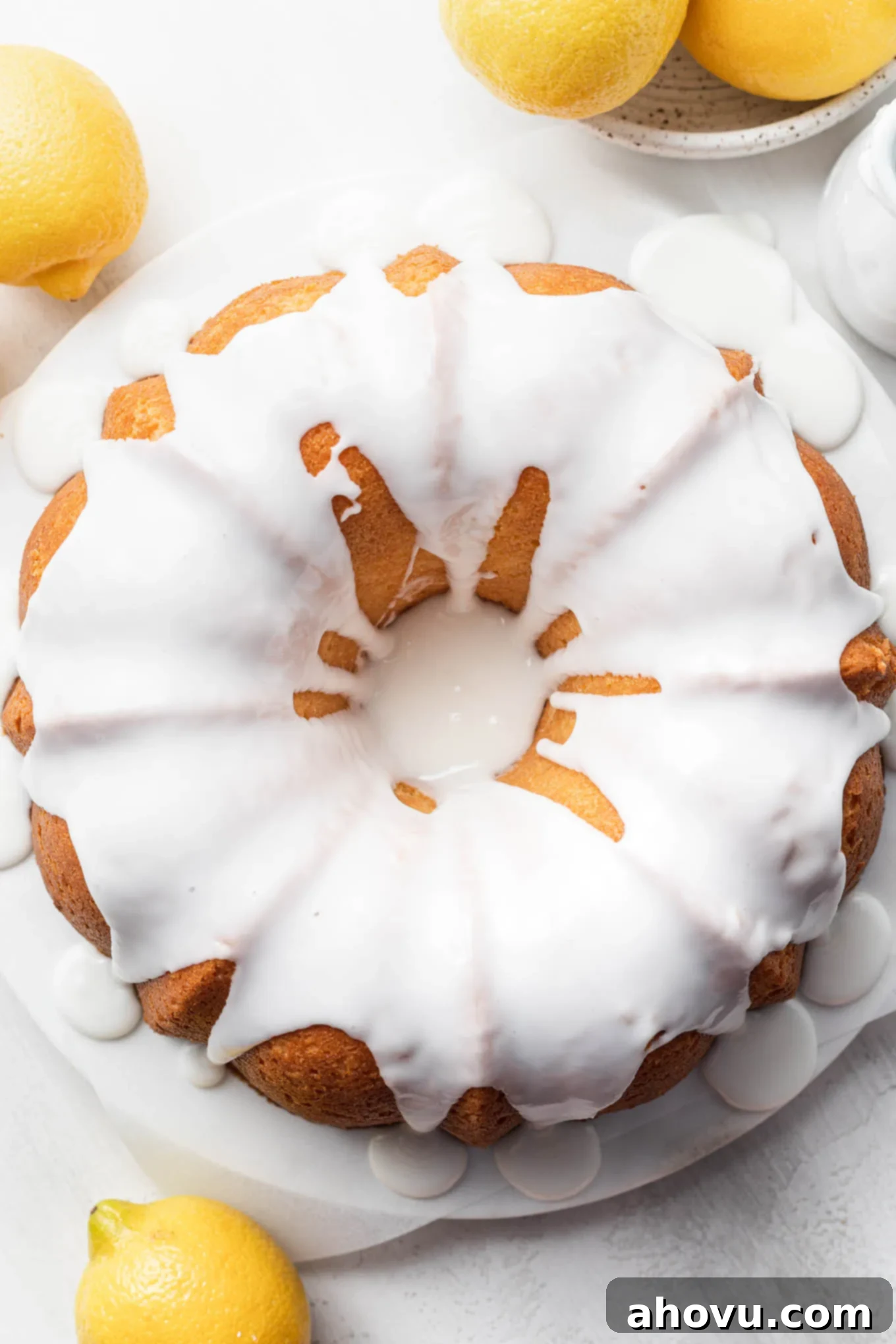 An overhead view of a lemon pound cake topped with glaze, surrounded by lemons. 