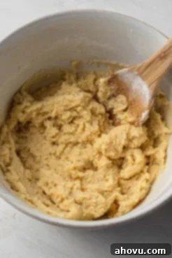 Thick cake batter in a white mixing bowl with a wooden spoon.