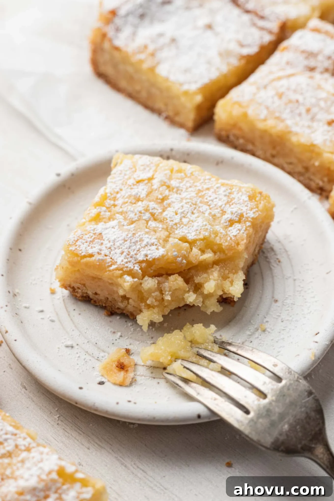 Golden Gooey Delight 5 A slice of ooey gooey butter cake on a dessert plate, with a bite missing.