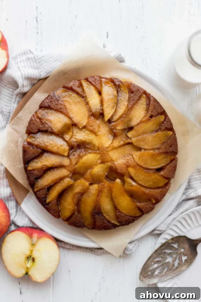 An overhead view of an apple upside-down cake with beautifully sliced apples and milk around it, ready to be served.