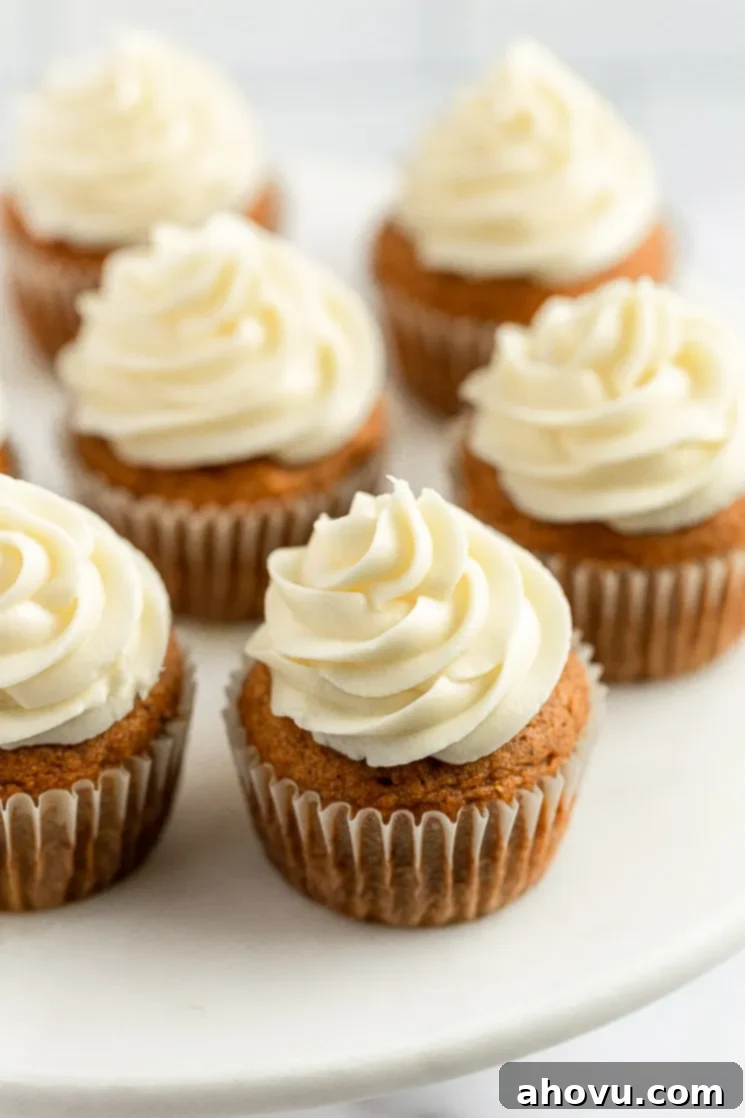 An inviting overhead shot of several pumpkin cupcakes, each perfectly frosted with creamy white cream cheese frosting, artfully arranged and ready to be enjoyed.
