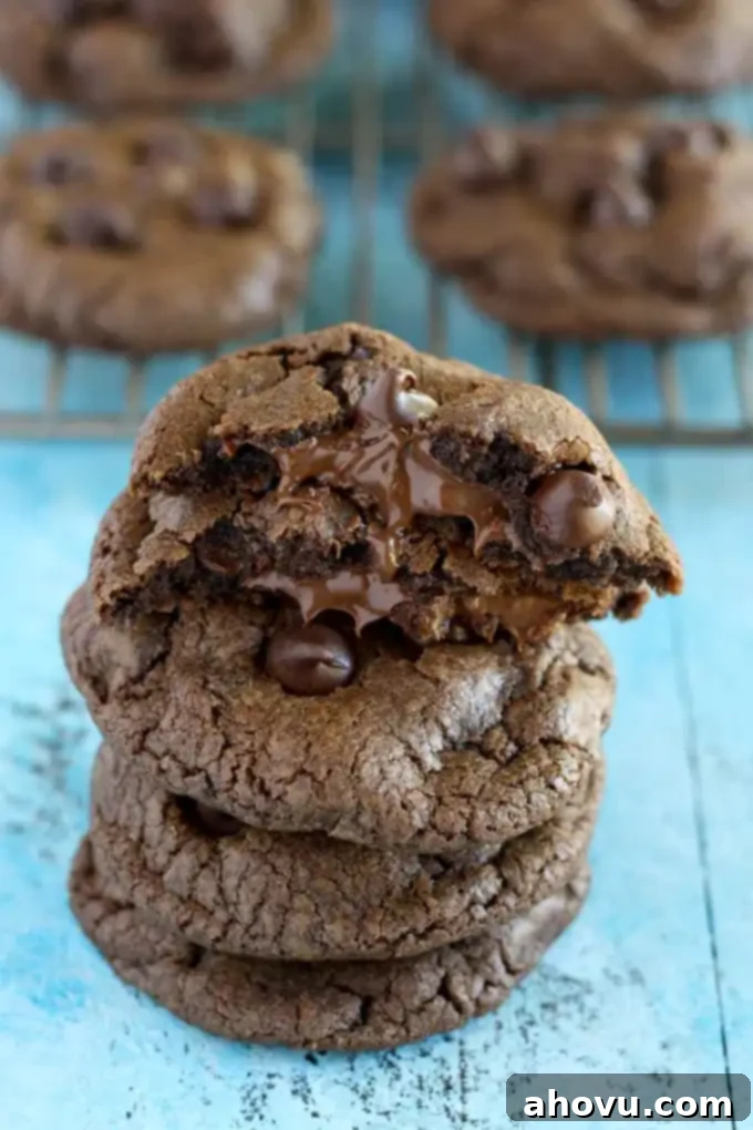 A stack of four nutella stuffed cookies. Additional cookies rest on a cooling rack in the background. 