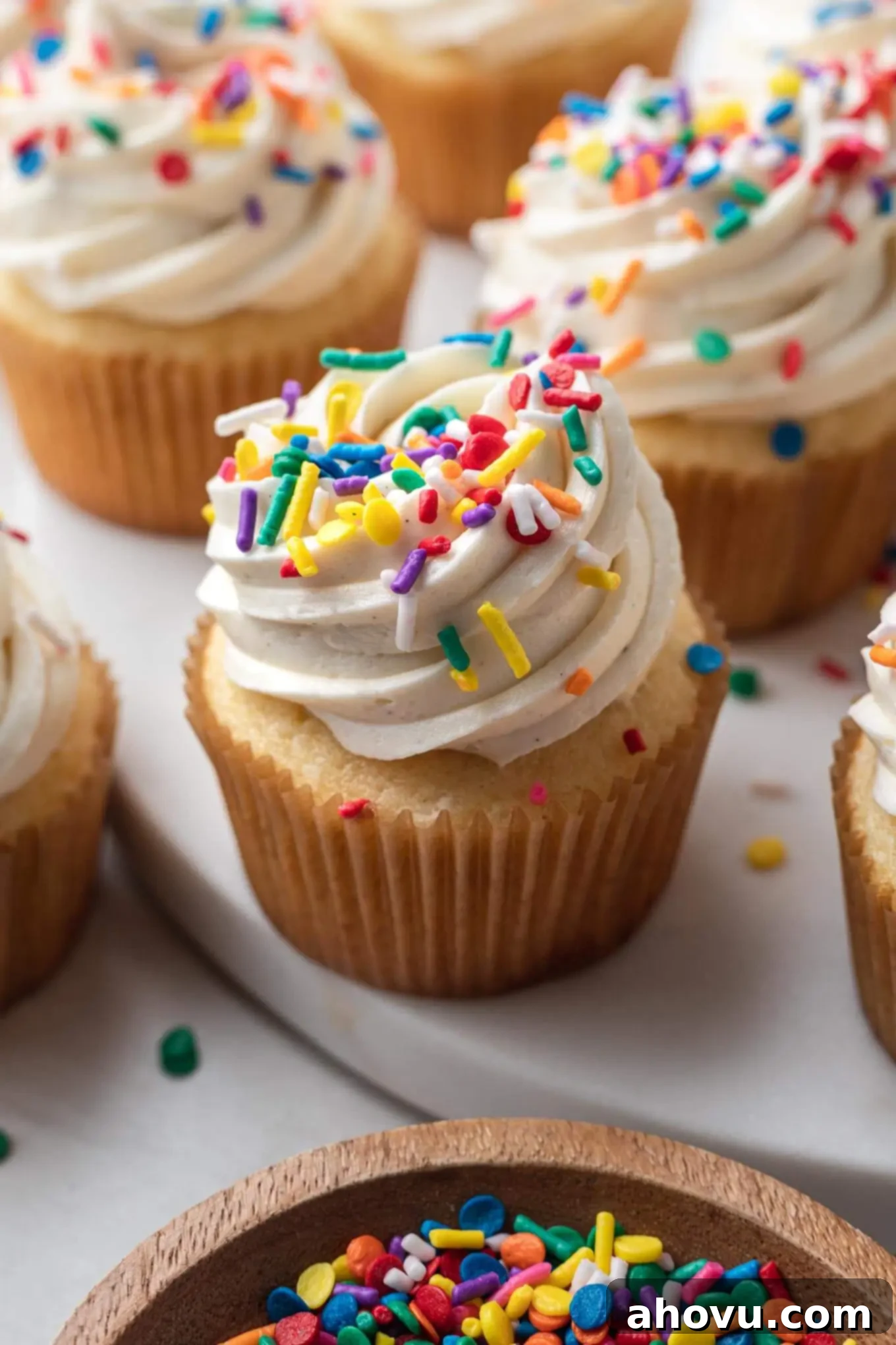 Homemade vanilla cupcakes topped with frosting and sprinkles. 