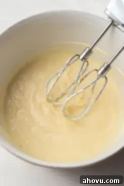 Wet ingredients for cupcakes in a mixing bowl with a handheld mixer.