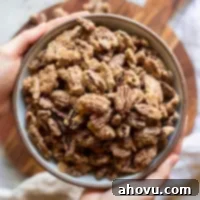Sweet Crunchy Homemade Pecan Perfection 6 A bowl of candied pecans, perfectly roasted and spiced, held invitingly over a rustic wooden surface, highlighting their homemade charm.