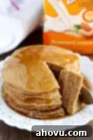 Cozy Gingerbread Flapjacks 6 A smaller, cropped image showing a stack of fluffy gingerbread pancakes topped with powdered sugar and maple syrup, complementing the full recipe card.