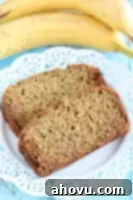 A slice of whole wheat banana bread on a small plate, with a background of a full loaf.