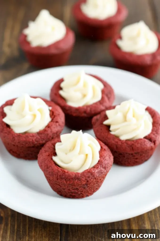 Red Velvet Cookie Bites 4 Four perfectly frosted deep dish red velvet cookies with cream cheese frosting arranged on a clean white plate.