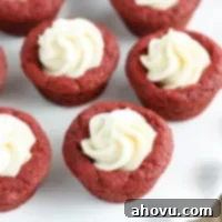 Red Velvet Cookie Bites 5 A close-up shot of a red velvet cookie cup with cream cheese frosting, ready to be enjoyed.