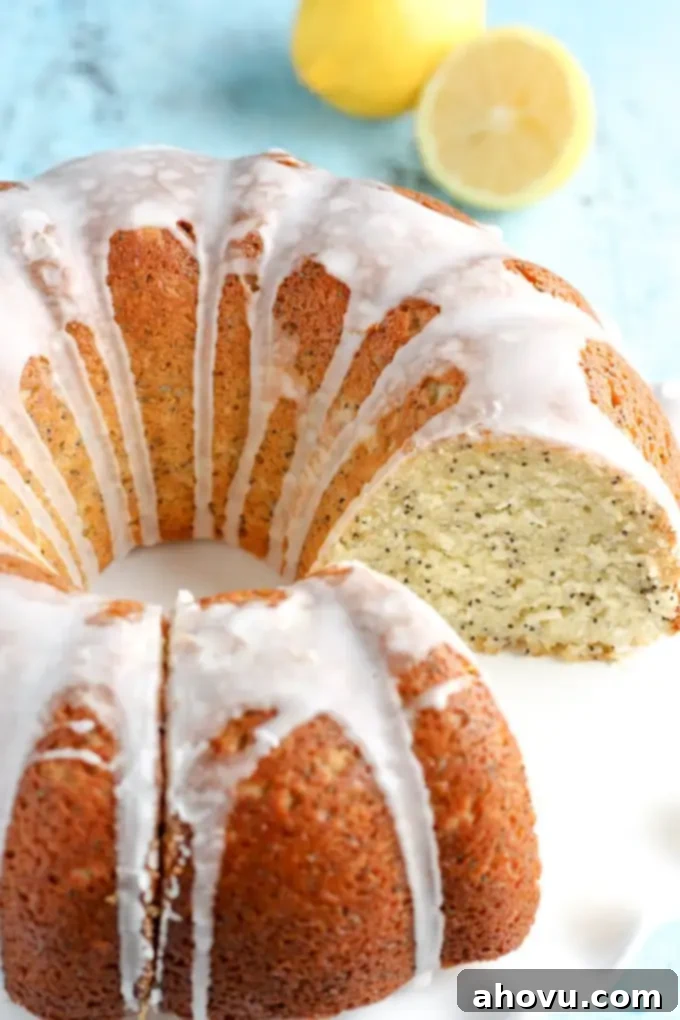 A gloriously glazed lemon bundt cake rests on a pristine white cake stand. A single, perfect slice has been carefully removed, revealing the soft, lemony interior.