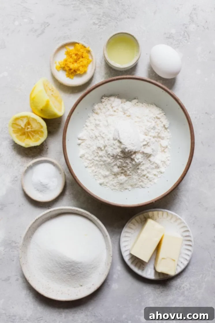 The simple, fresh ingredients required to bake a batch of soft lemon cookies, neatly arranged on a rustic gray surface, ready for preparation.