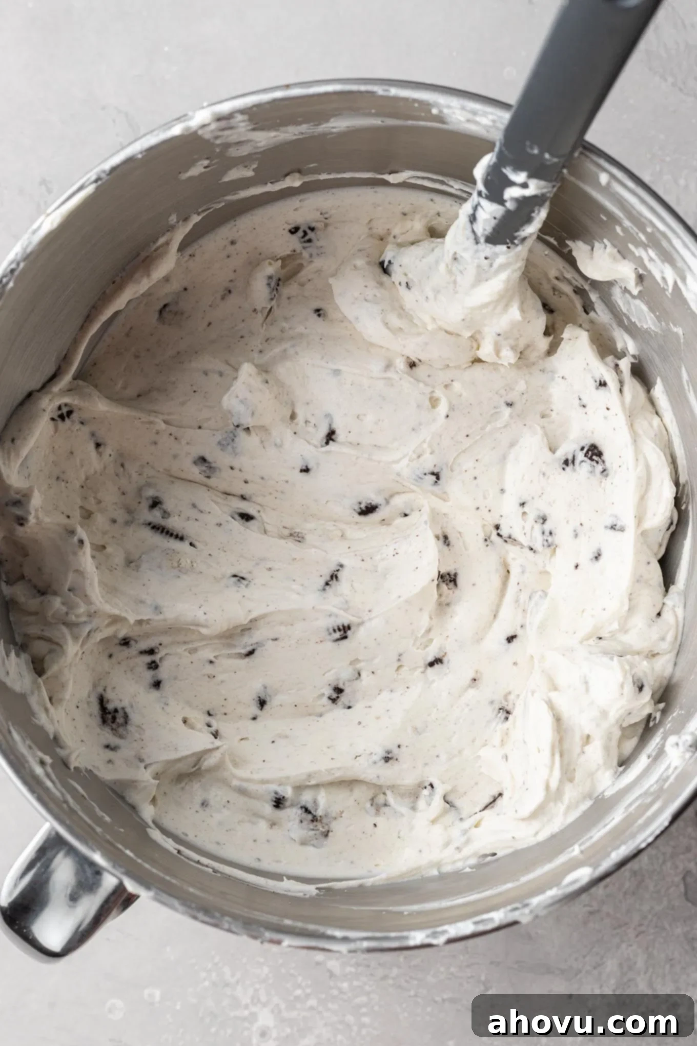 Decadent No-Bake Oreo Cheesecake 7 Oreo cheesecake filling in the bowl of a stand mixer, showing whipped cream and Oreos folded into the cream cheese mixture.