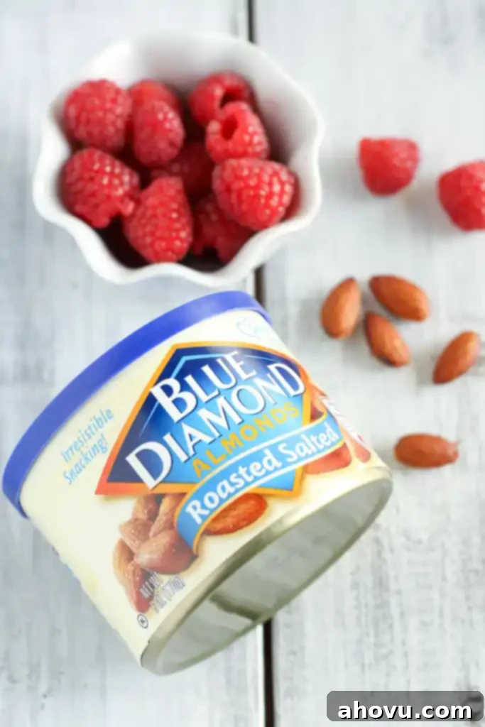 A container of almonds and a dish of fresh raspberries. 