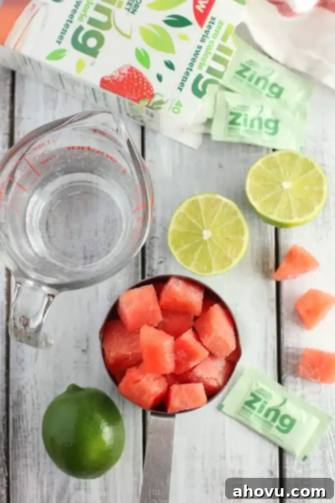 Watermelon Zest Cooler 3 Two glasses of frosty watermelon lime slushies, one with a green straw and a lime wedge, placed on a light wooden surface in natural light.