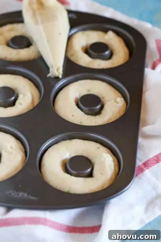 Key lime donut batter piped into a donut pan, perfectly portioned and ready to be baked into delicious treats.