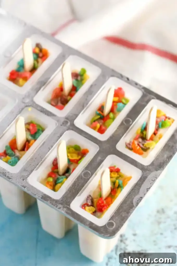 Pouring the Marshmallow Fruity Pebbles pudding mixture into a popsicle mold.