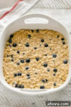 A white baking dish evenly filled with the unbaked blueberry banana baked oatmeal mixture, prepared for baking.