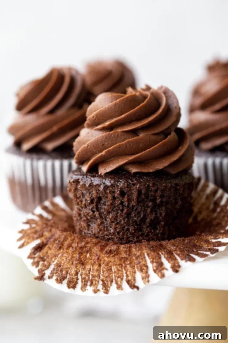 A marble cake stand holding chocolate cupcakes topped with chocolate frosting.