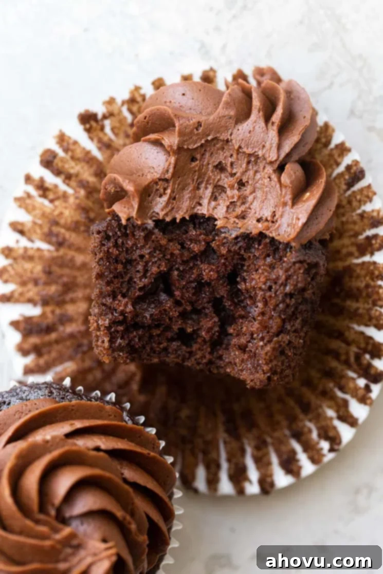 A chocolate cupcake on its side with a bite taken out to show the cake and frosting texture.