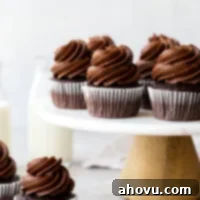 Several chocolate cupcakes on top of a marble cake stand.