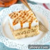 A delicious slice of No-Bake Pumpkin Caramel Icebox Cake with layers of graham crackers, pumpkin spice cheesecake, and caramel, topped with whipped cream.