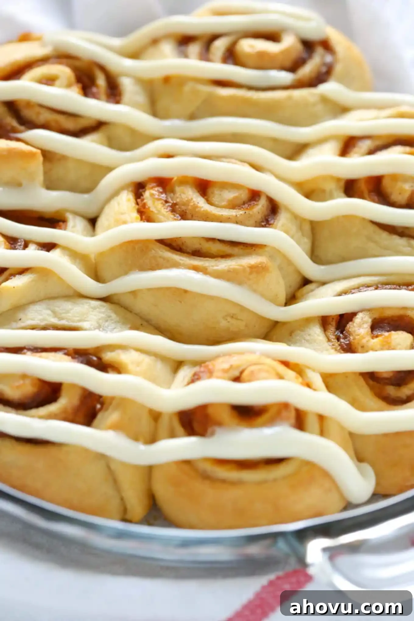 A baking dish filled with crescent roll cinnamon rolls generously topped with cream cheese frosting.