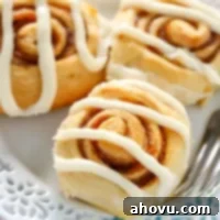 A close-up of a single pumpkin cinnamon roll with cream cheese frosting.