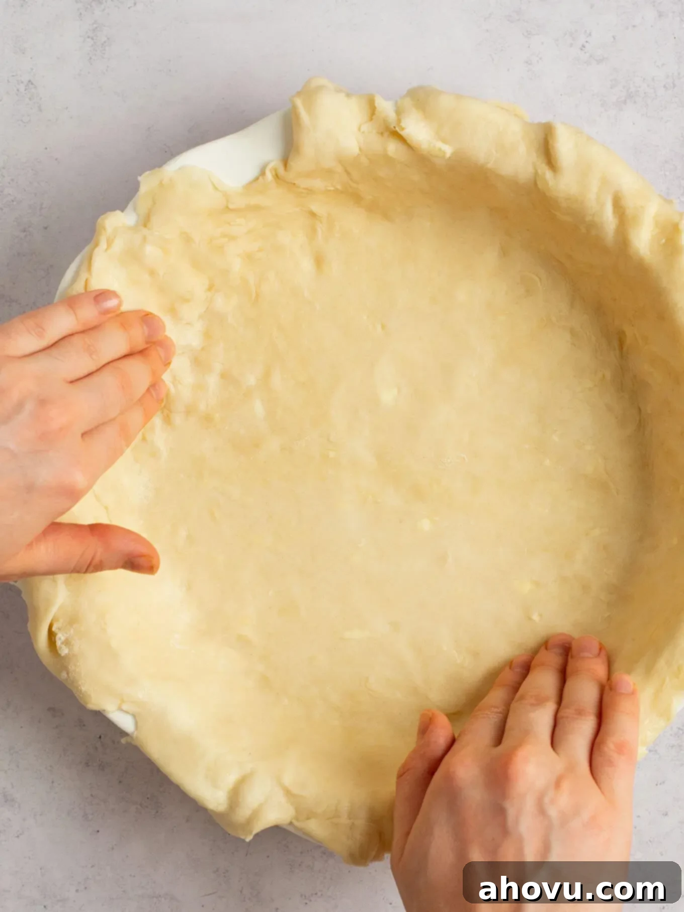 Spiced Pumpkin Perfection 5 Delicate pie dough being carefully fitted into a white ceramic pie dish, ensuring an even base for the pie.