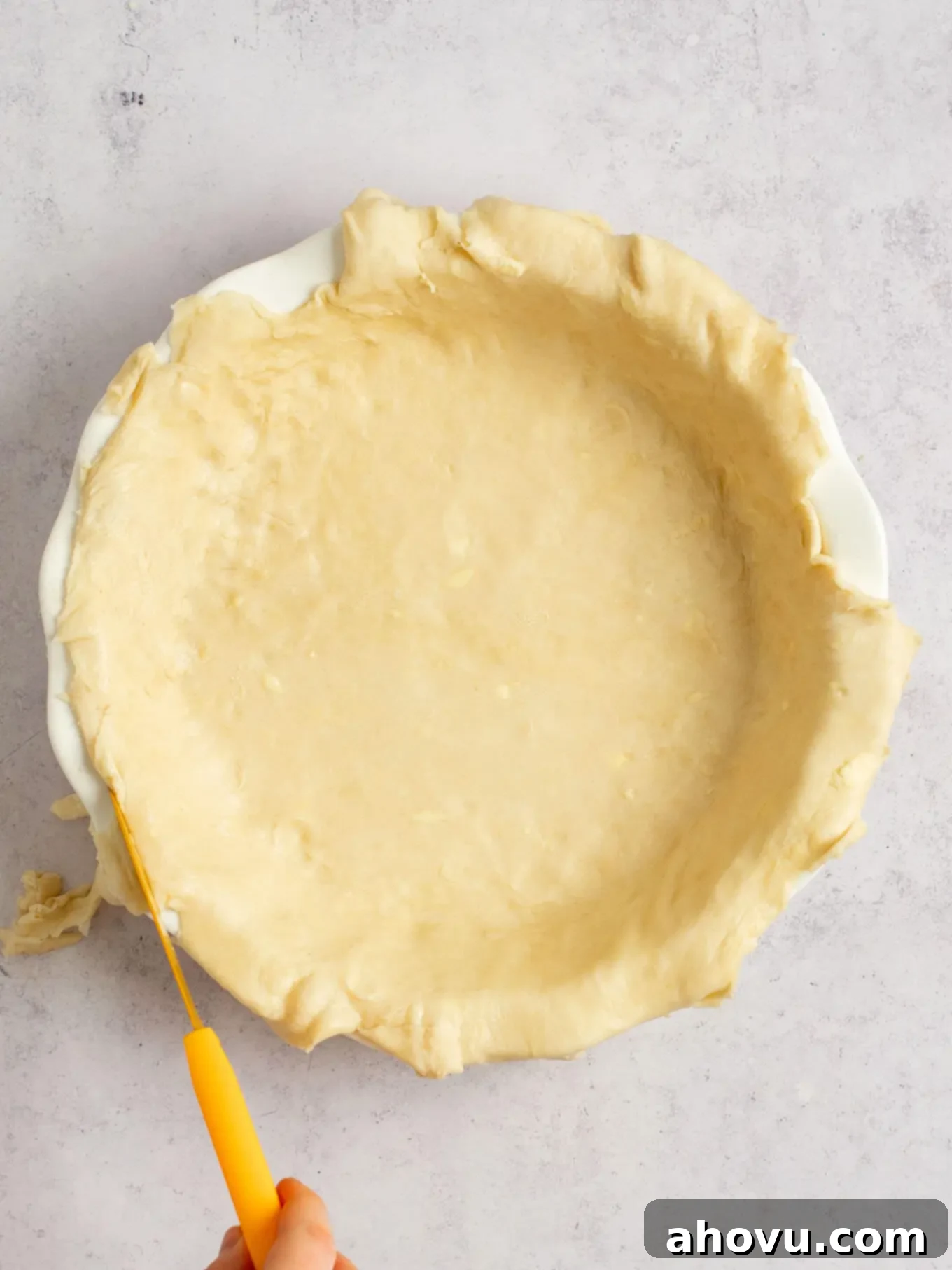 Spiced Pumpkin Perfection 6 An overhead view of pie dough in a pie dish, with a knife expertly trimming the excess edges for a neat finish.