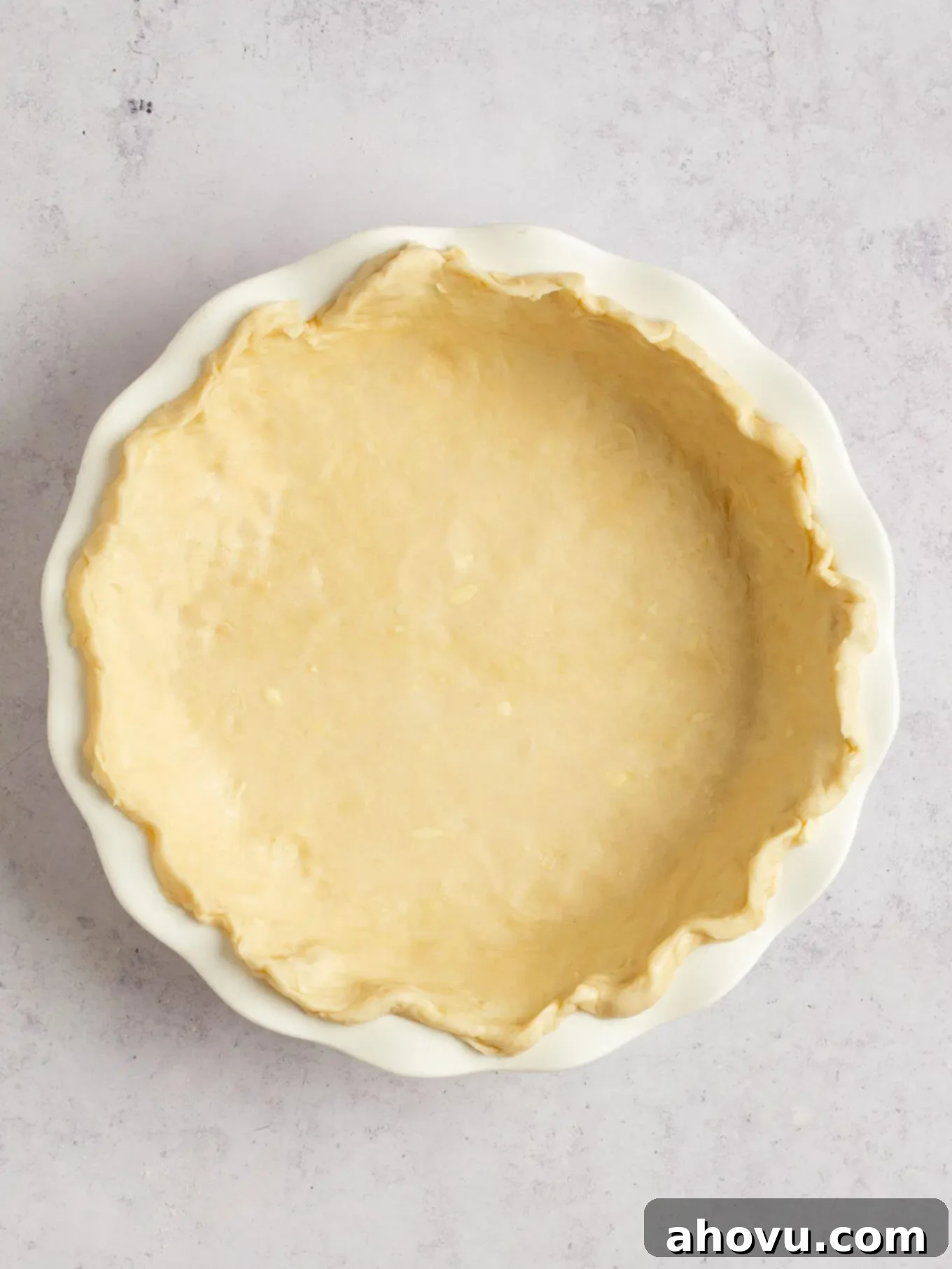 Spiced Pumpkin Perfection 7 A pristine pie dough beautifully crimped along the edges, nestled in a white ceramic pie dish, showcasing neat craftsmanship.