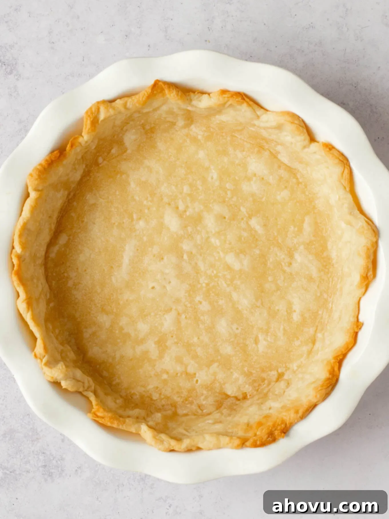 Spiced Pumpkin Perfection 10 A partially baked, golden-brown pie crust resting perfectly in a white ceramic pie dish, ready for its delicious filling.