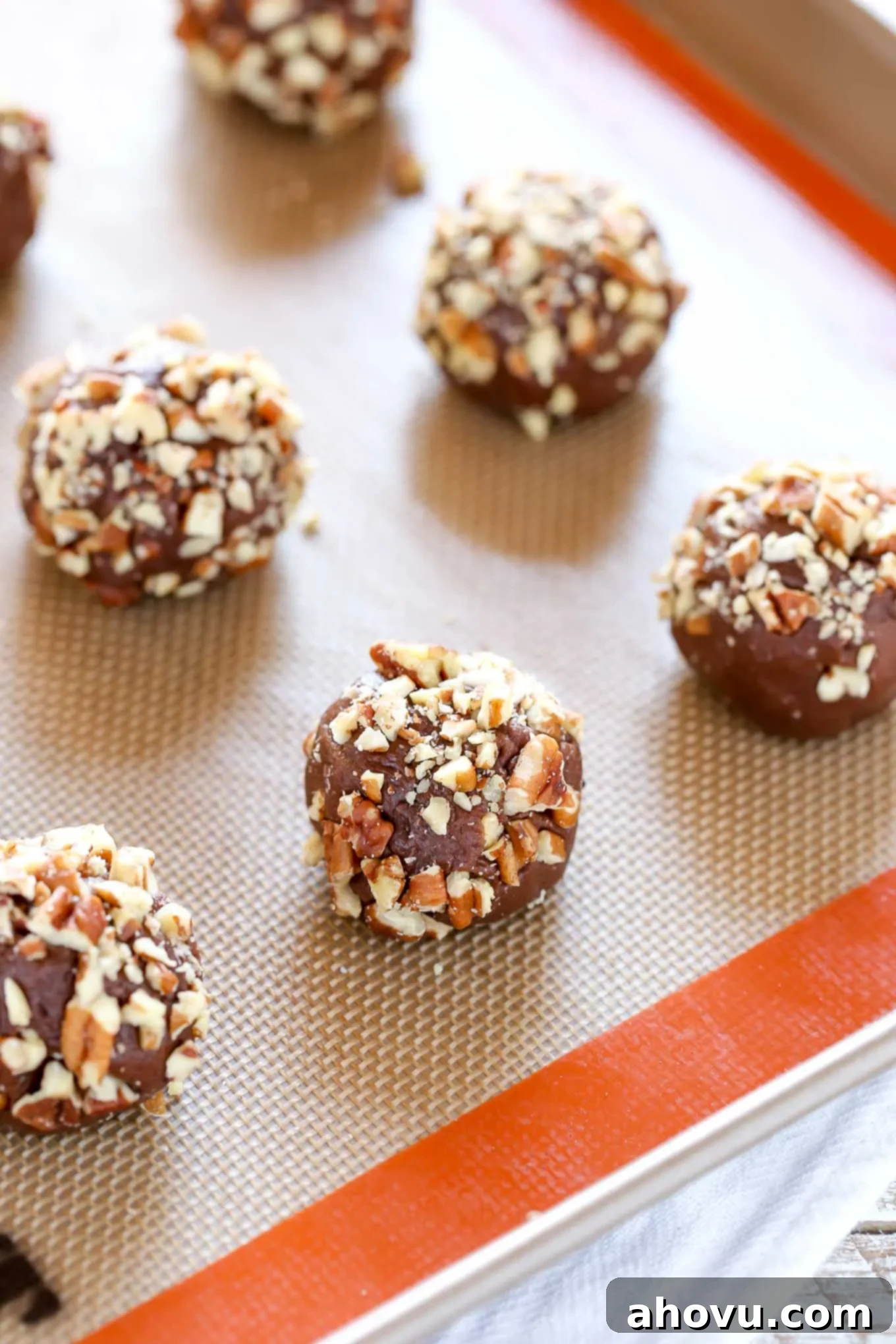 Unbaked balls of turtle cookie dough on a Silpat-lined baking tray. 