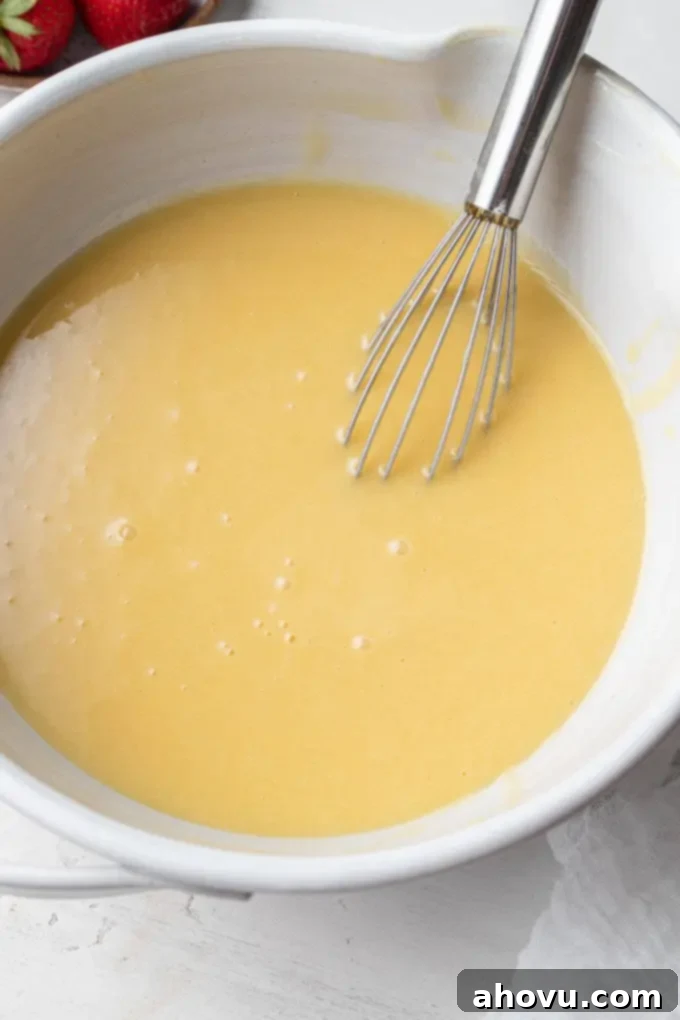 A close-up of a mixing bowl containing a smooth, golden egg yolk mixture, expertly whisked to perfection and ready for the next step in the chiffon cake recipe.