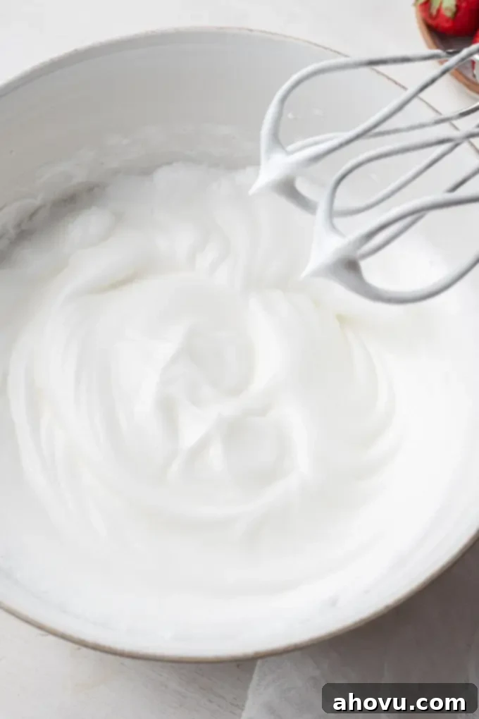 A vibrant image of fluffy, white egg whites, perfectly beaten to stiff peaks in a glass mixing bowl, showcasing their robust and stable texture.