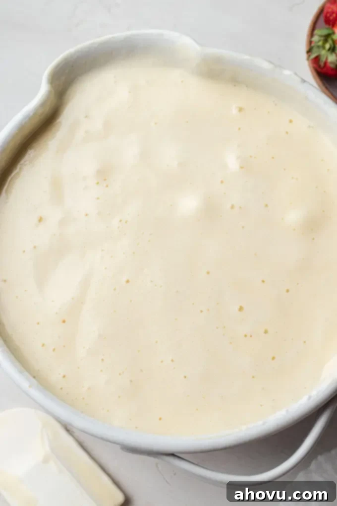 A close-up shot of the chiffon cake batter, showing the delicate process of folding in whipped egg whites, creating a light and airy consistency with visible streaks.