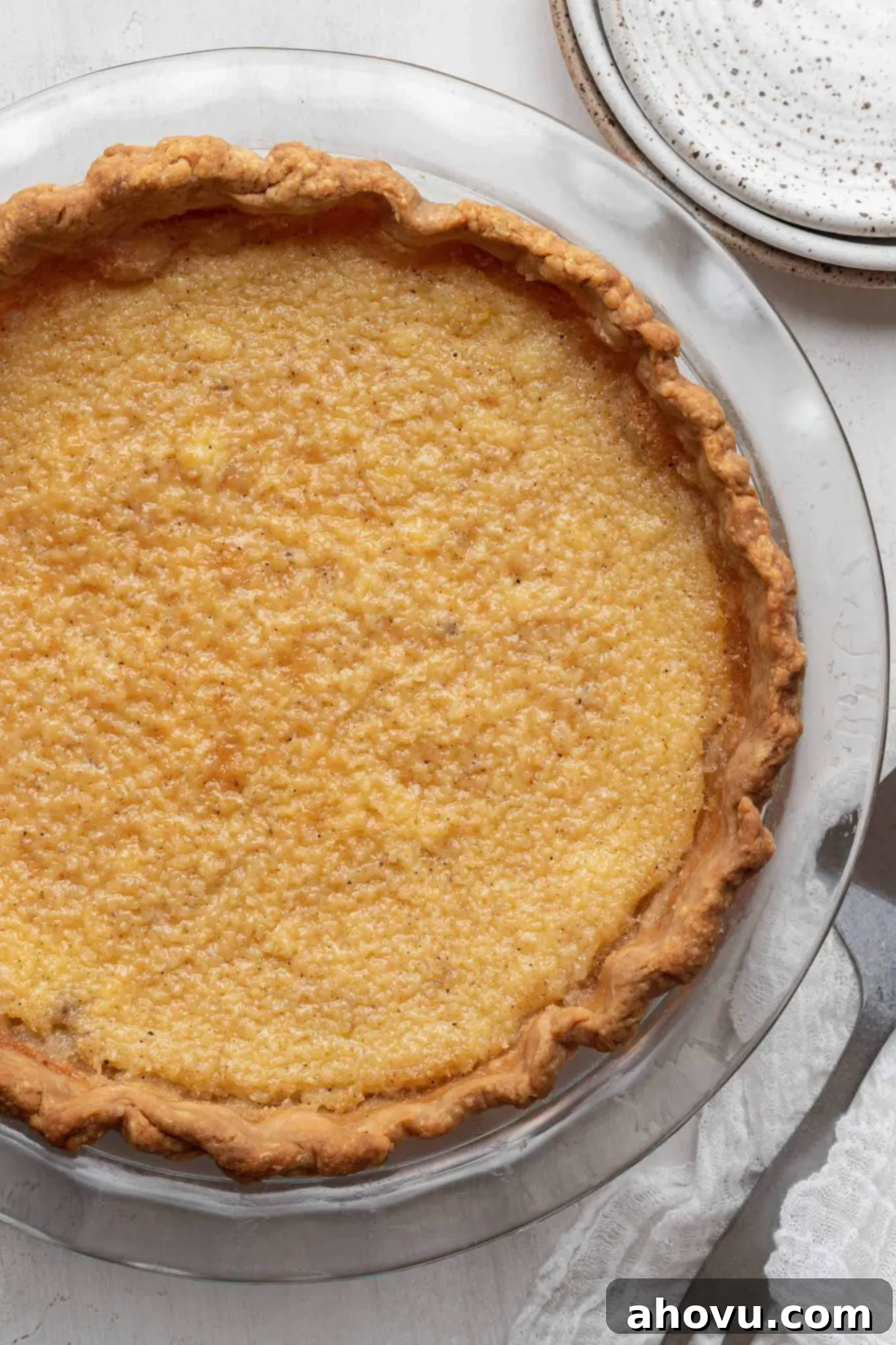 An overhead view of a baked buttermilk pie in a glass pie plate.