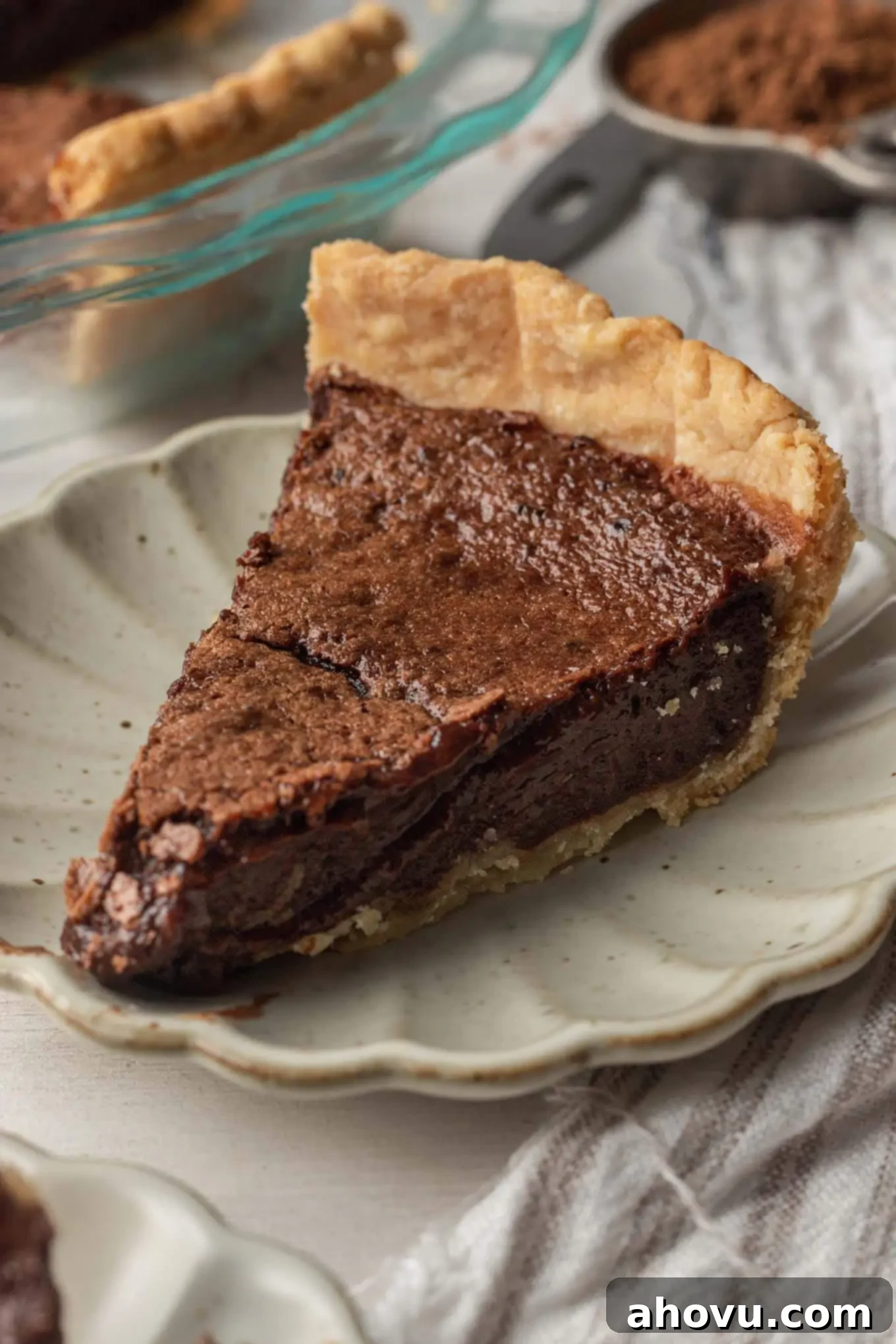 Heirloom Chocolate Pie 2 A beautifully presented slice of homemade chocolate chess pie on a scalloped cream plate, showcasing its rich, fudgy texture and golden crust.