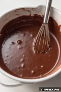 A rich, glossy chocolate batter for the chess pie filling in a white mixing bowl, being whisked to achieve a smooth consistency.