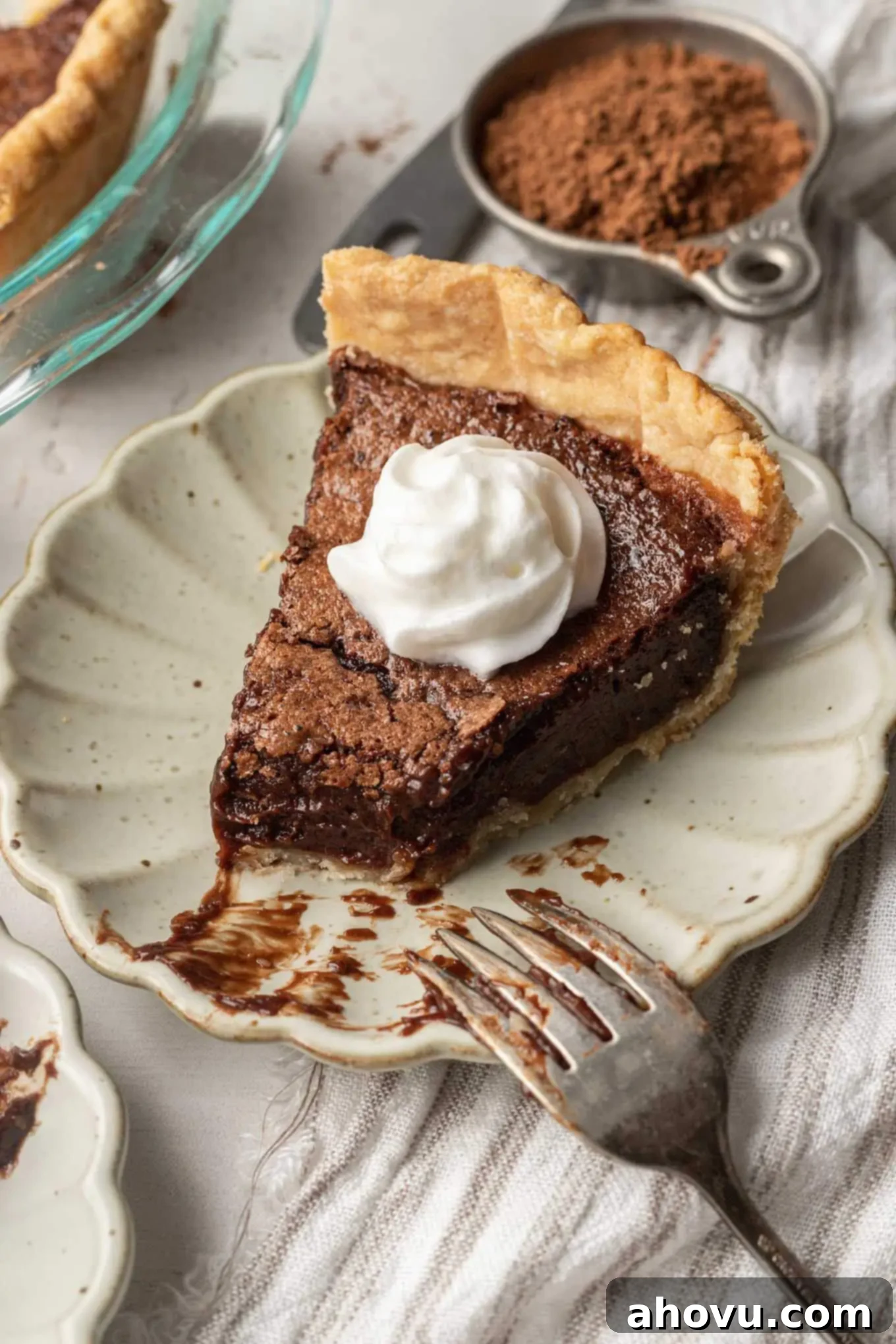 Heirloom Chocolate Pie 8 A close-up shot of a single slice of chocolate pie on a white plate, with a bite missing, and a fork resting beside it, highlighting the smooth filling.