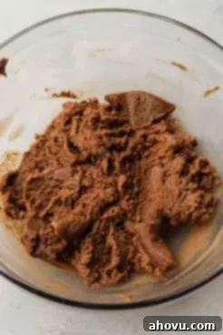 An overhead view of almond butter cookie dough in a mixing bowl.