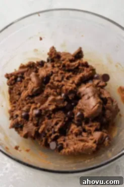 An overhead view of almond butter cookie dough with chocolate chips in a mixing bowl.