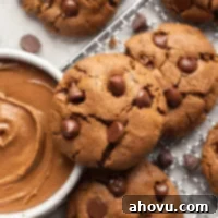 Several almond butter cookies on a wire rack. A bowl of almond butter is next to the cookies.