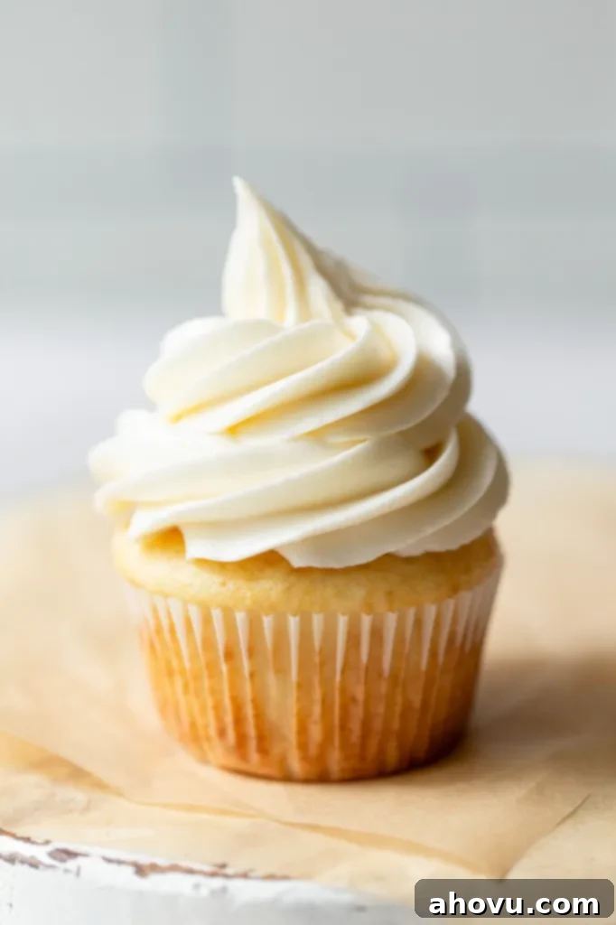 A single cupcake topped with buttercream frosting on top of brown parchment paper.
