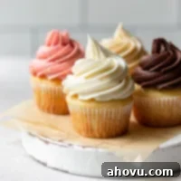 Four cupcakes topped with different flavors of buttercream frosting sitting on a rustic cake stand.
