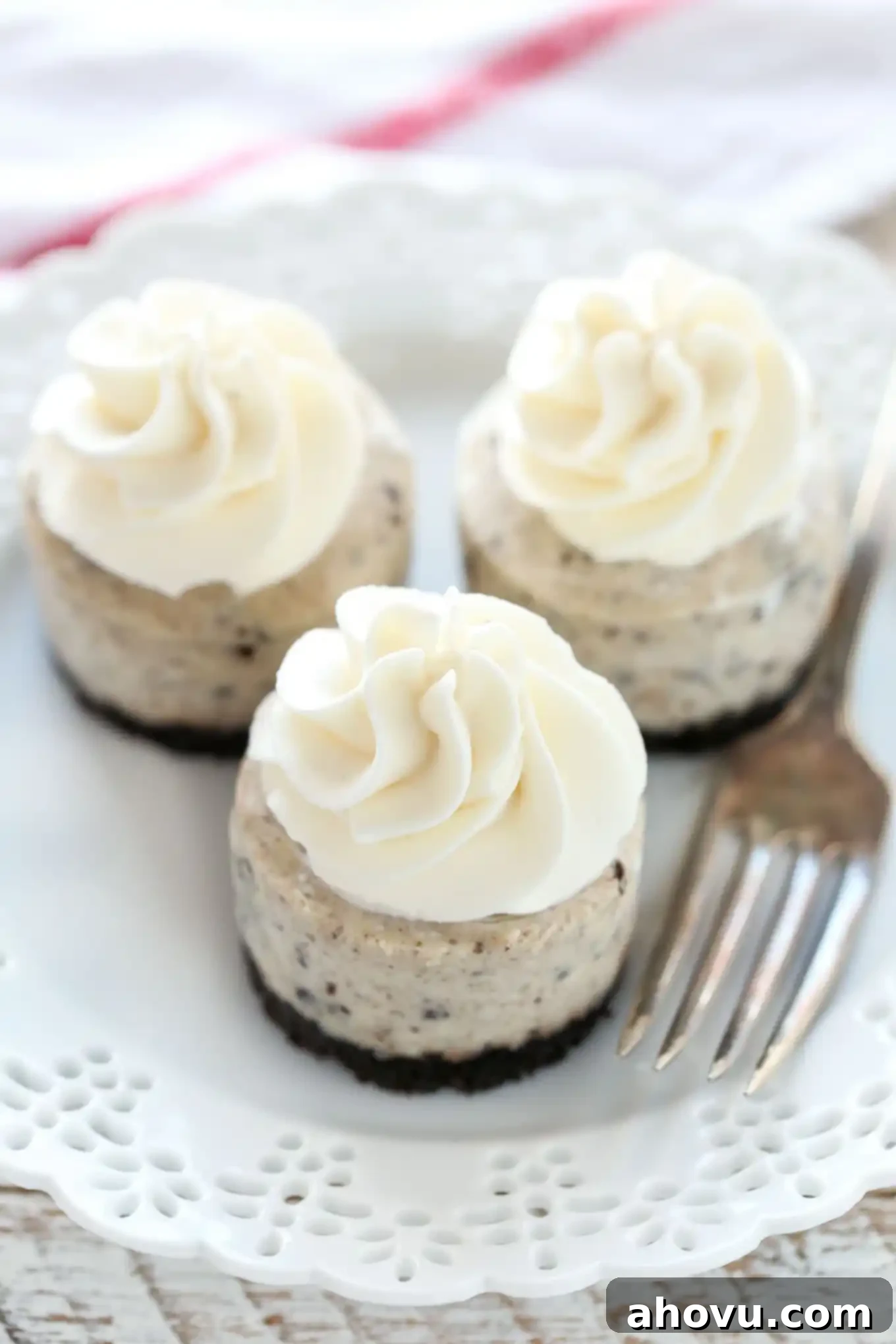 Oreo Cookie Cheesecake Bites 2 Three mini Oreo cheesecake bites on a white plate with a fork, highlighting the creamy texture and Oreo crust.
