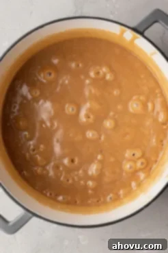 An overhead view of thickened, bubbling caramel in a saucepan.