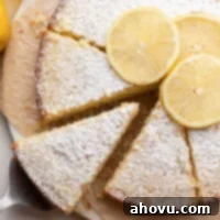 Sun-Kissed Lemon Olive Oil Cake 7 A sliced lemon olive oil cake on a piece of parchment paper. Once slice is being removed.