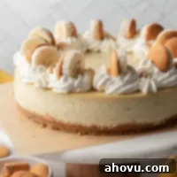 Banana Pudding Cheesecake 9 A banana pudding cheesecake on top of a marble cake stand. The cheesecake is topped with swirls of whipped cream, sliced bananas, and Nilla wafers.